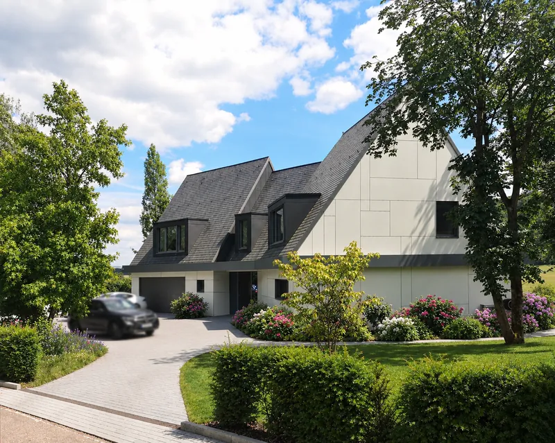 Extension de maison à Waldbredimus vue depuis l'allée : façade en panneaux blancs et toiture en ardoise